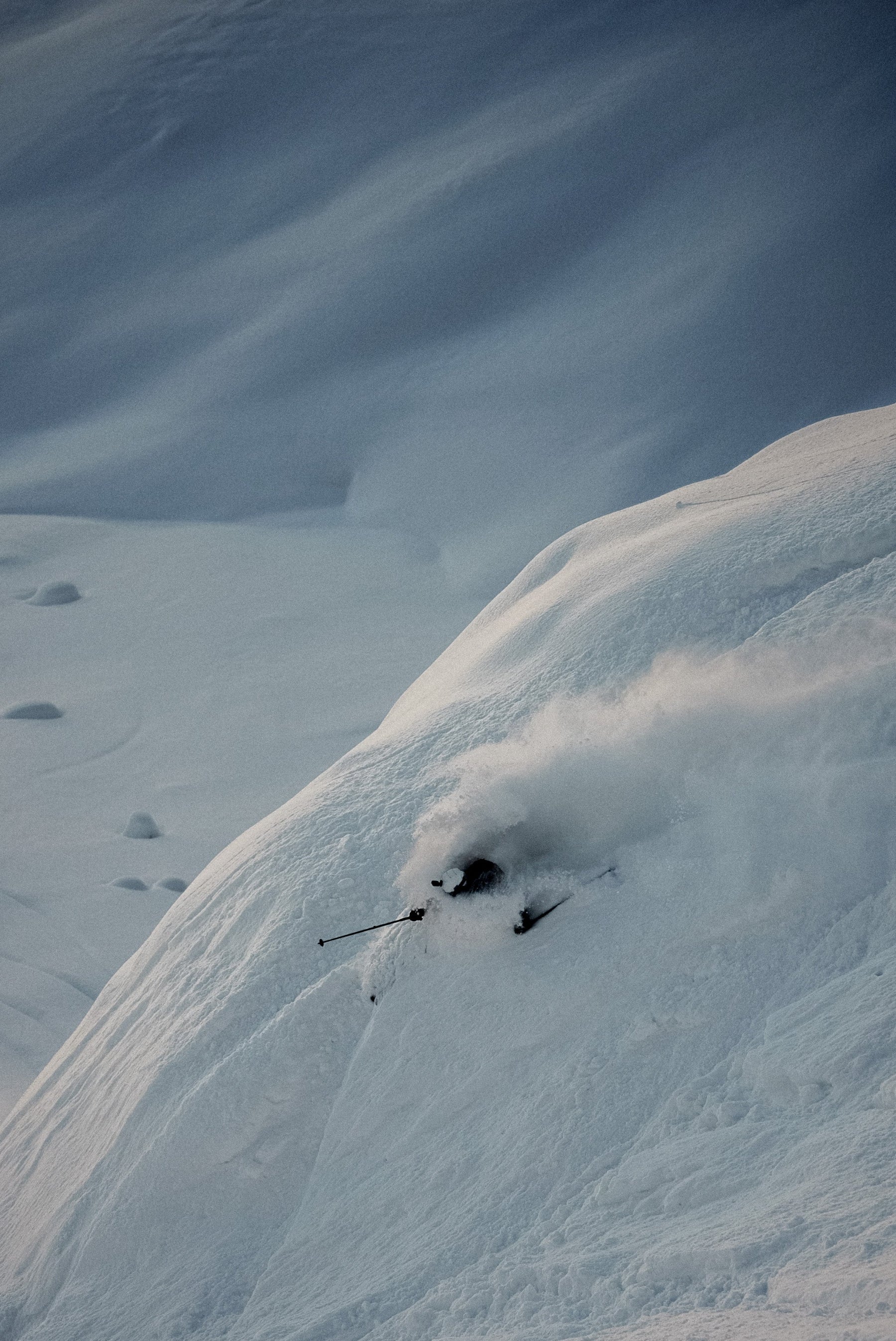 Skier making a turn through deep powder during a ski touring adventure.