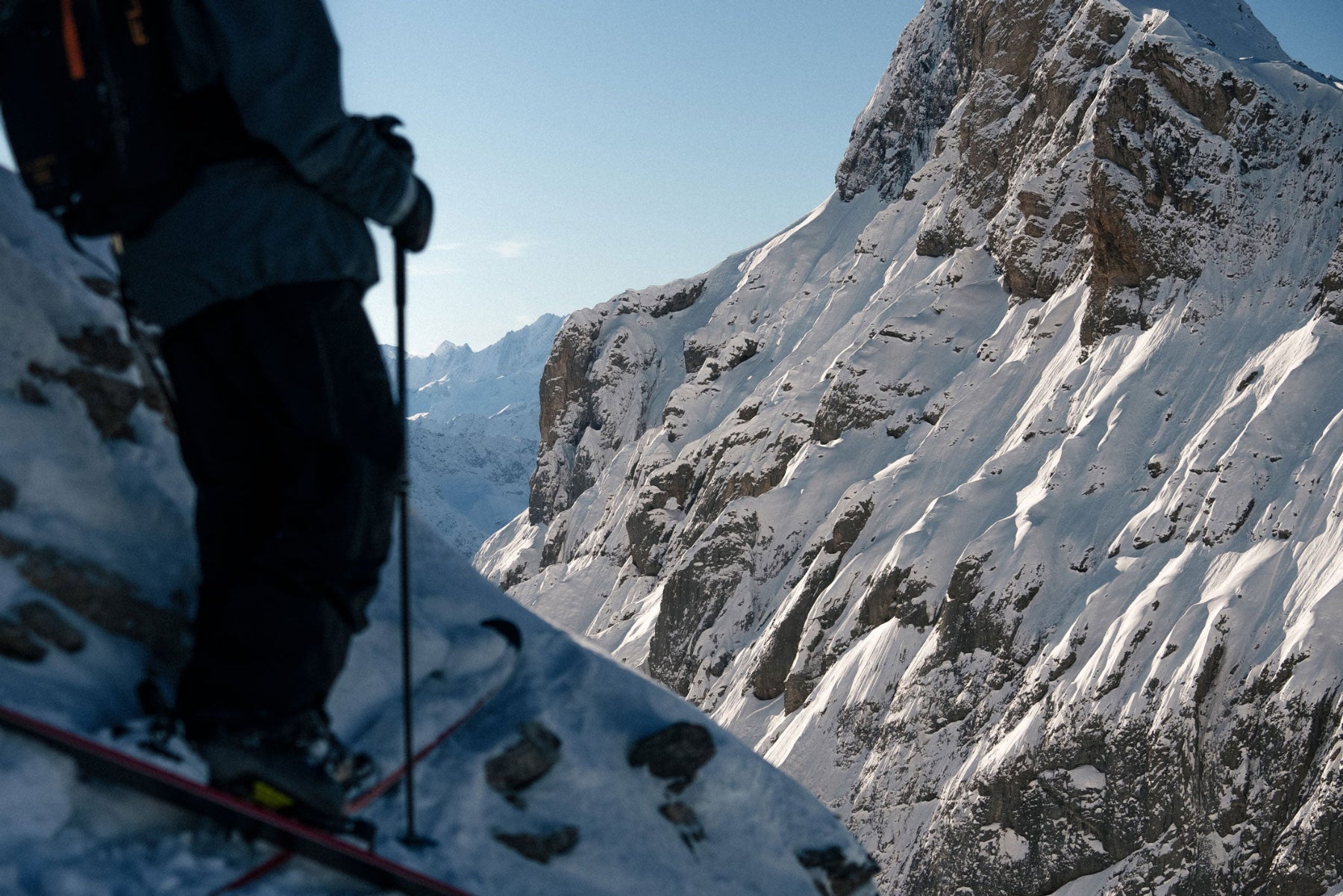 Skier overlooking alpine mountains during a ski touring adventure.